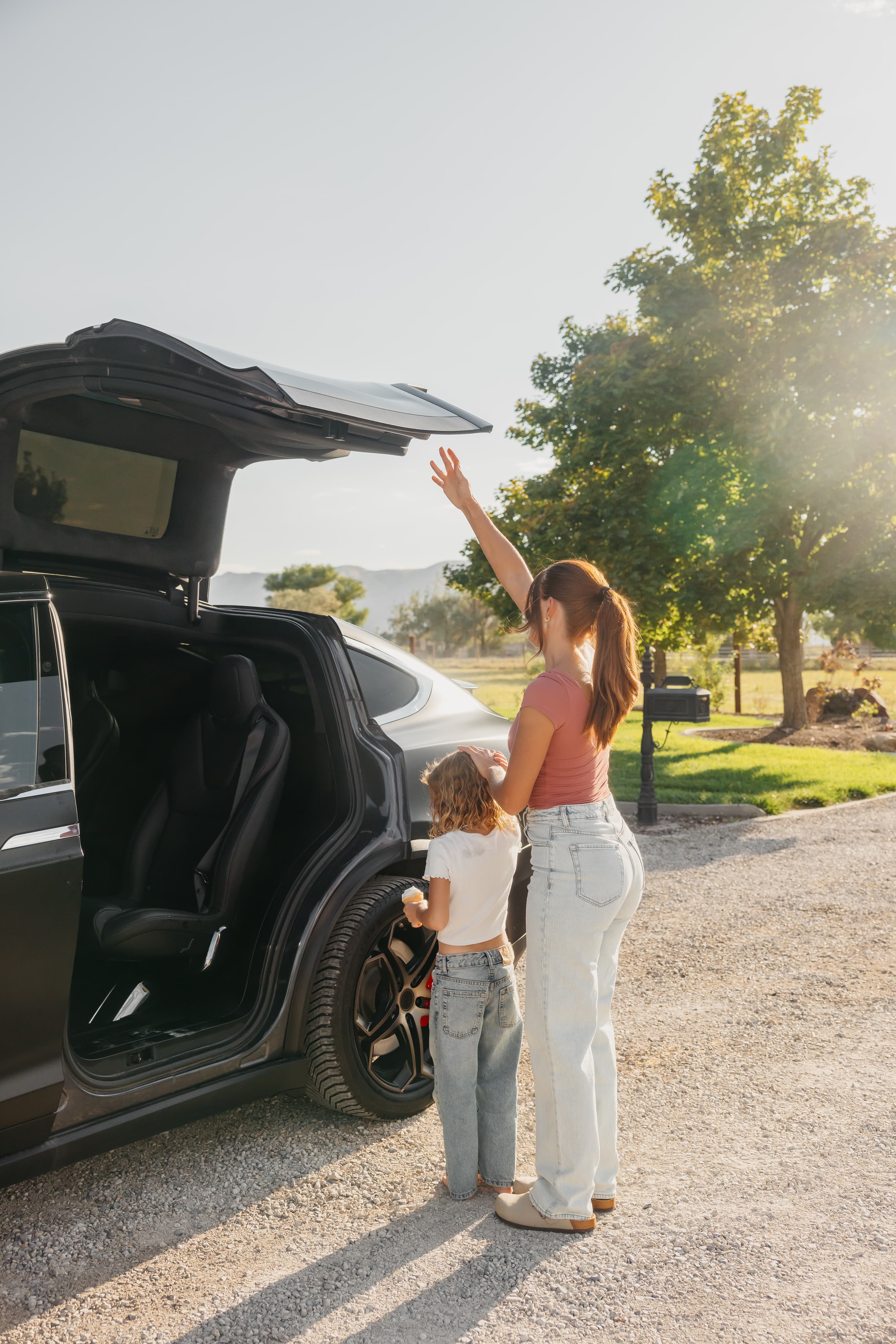 A parent and child beside an electric vehicle outdoors