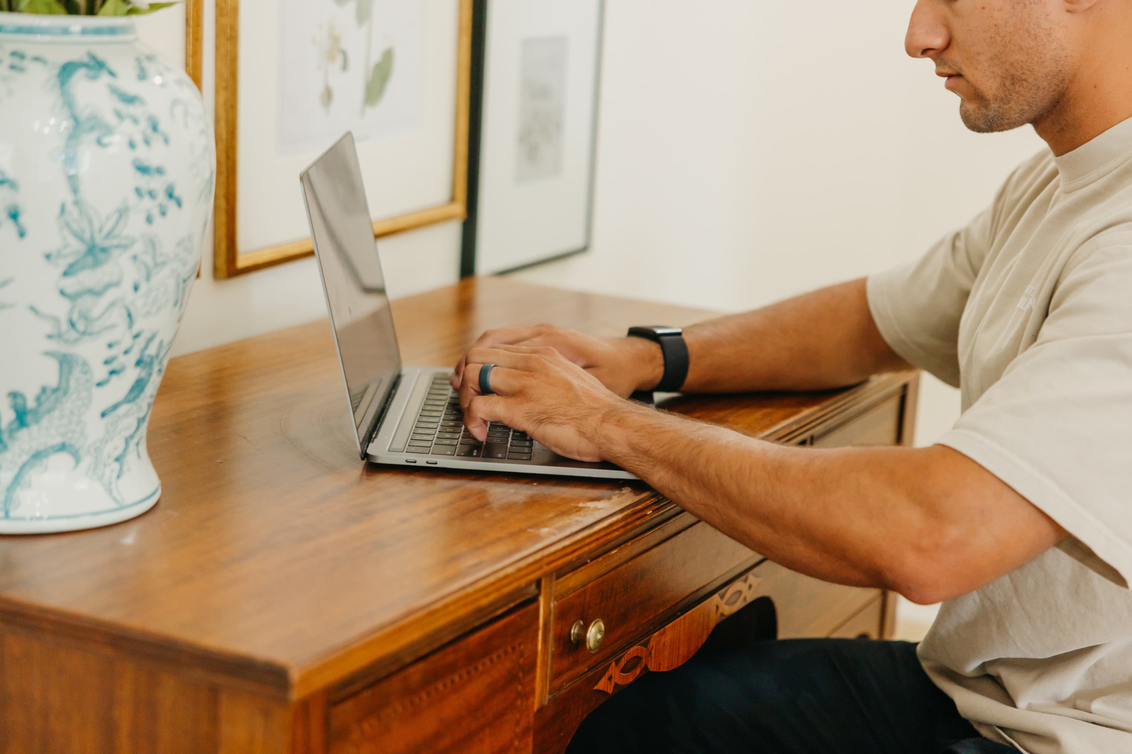 A person typing on a laptop at a wooden desk